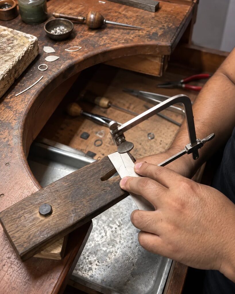 Corte de uma peça com arco de serra na bancada do ateliê
